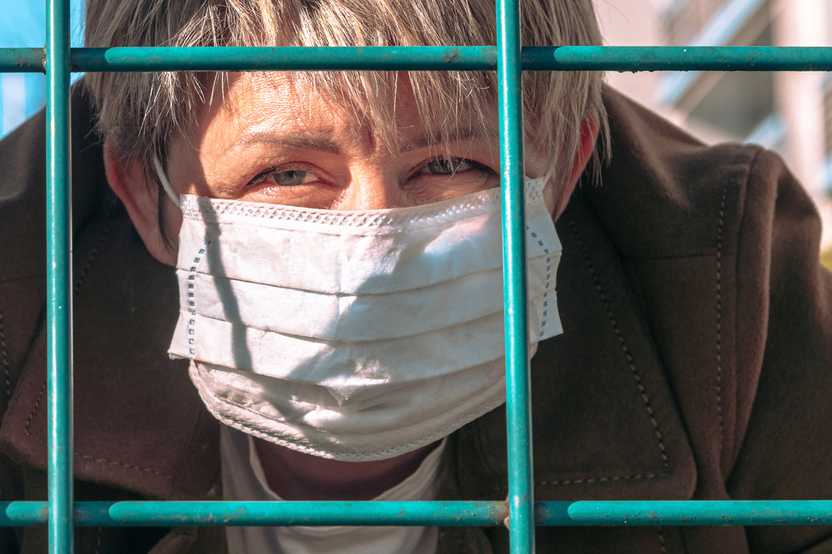 woman wearing face mask behind bars