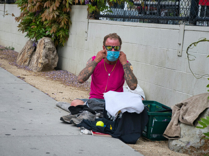homeless man puts on his coronavirus mask